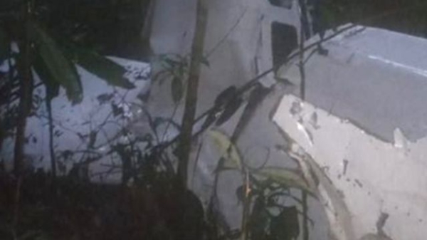 A crashed plane, nose down surrounded by dense rainforest